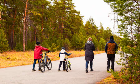 Family with children is walking in the autumn park. Children ride bicycles. Family walk, weekend.