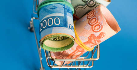 Russian rubles in a grocery basket on a blue background. Financial crisis, ruble devaluation concept. Selective focus.の写真素材