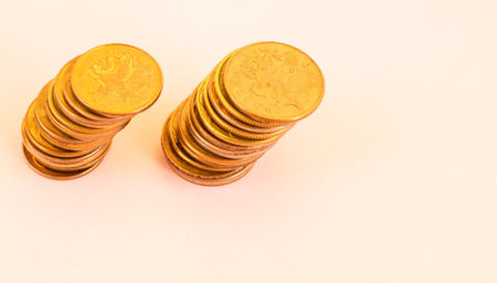 Money coins in a stack are tilted to the side, isolated on a light background. Bundles of coins...