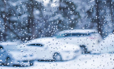 Water drops on the surface of window panes. View of the parked cars from the wet window. Selective focus. Blurred background.の写真素材