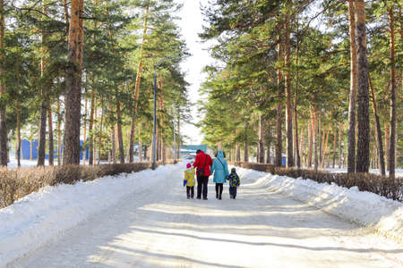 A family with children walks in a winter park on a sunny day. Bright winter landscape. Family joint outdoor recreation. Copy space.の写真素材