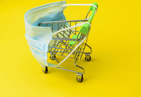 Miniature supermarket trolley and medical mask. Quarantine restrictions concept.の写真素材
