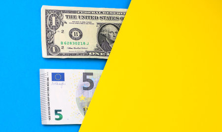 Banknotes of the USA and Europe isolated on yellow and blue background. Colors of the flag of Ukraine. Ukrainian financial crisis. Currency exchange concept. Money background. Copy space.の写真素材