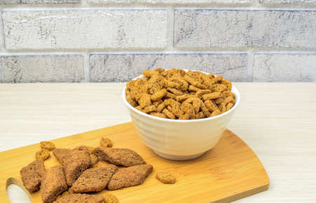 Crispy appetizing croutons in a white plate on a wooden kitchen board, against a brick wall...