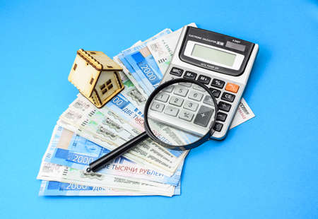 Miniature toy house, Russian rubles, magnifying glass, calculator on a colored background. Real estate object. Concept of buying an apartment, house. Rental of property.の写真素材