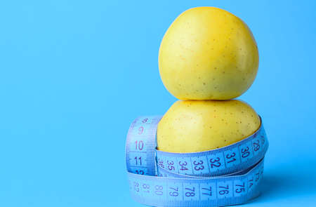 Two yellow apples wrapped in a centimeter tape. Healthy food, calorie content. Fitness, diet, weight...