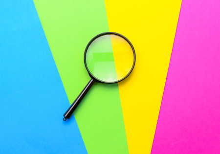 Magnifying glass on multi-colored paper. Top view. Copy space for text.の写真素材