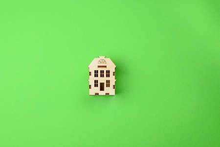 Miniature wooden toy house on a bright green background. Real estate object. Concept of buying an apartment, house, real estate. Copy space. Flat lay.の写真素材