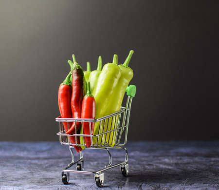 Colored chili peppers in a supermarket basket on a dark blurred background. Selective focus. Top view and side view.の写真素材