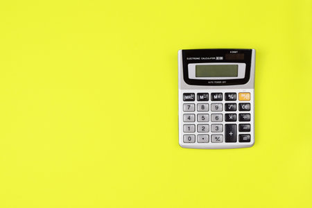 Calculator isolated on bright yellow background. Accounting concept, calculating payments. Home bookkeeping. Place for your text. Top view, flat lay.の写真素材