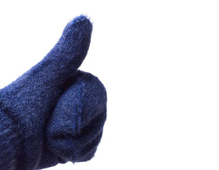 Hand in woolen blue mitten showing thumb up, isolated on white background. A positive gesture.の写真素材