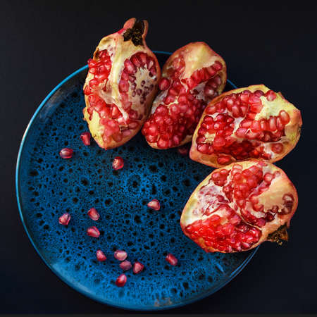 Ripe pomegranate on a round plate, dark background. Top view, flat lay.の写真素材