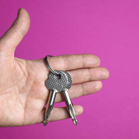 Two keys in the palm of a person on a colored background. Apartment purchase concept.の写真素材