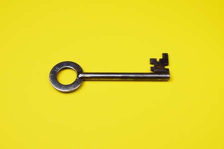 Old key on a yellow background, top view. Trendy colorful photo.の写真素材