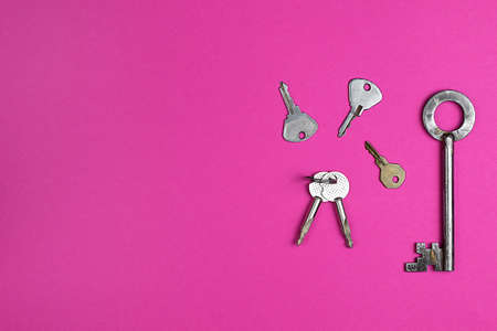 Keys on pink background, flat lay, trendy colorful photo with colored paper. Copy space.の写真素材