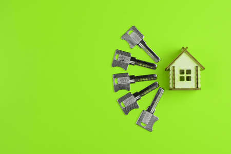 Wooden house model and house keys on a colored background. Real estate buying and selling concept. Top view, flat lay.の写真素材