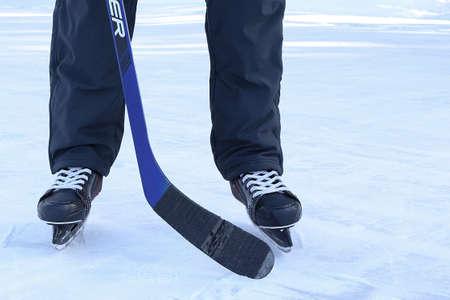 Russia, Chelyabinsk, February 14, 2022: Man plays ice hockey on a street rink. The lower body is...