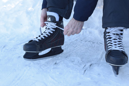 Athlete puts on hockey skates on a street skating rink.