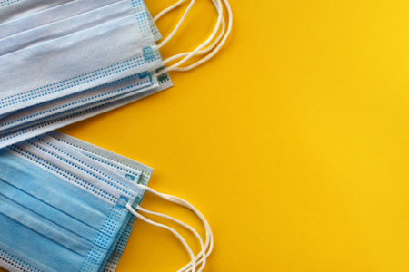 Colored medical masks on a yellow background. Protection against viruses and bacteria concept. Top view, flat lay. selective focus.の写真素材