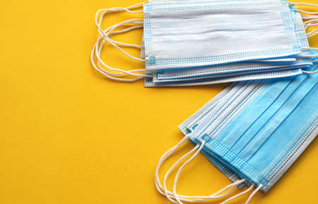 Medical protective mask on a yellow background. Coronavirus quarantine, hygiene, protection concept. Three-layer surgical mask. Virus protection concept. Top view, flat lay. copyspace.の写真素材