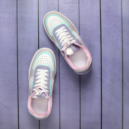 Fashionable women's sneakers for every day on a colored wooden background. Sports boots. minimal...