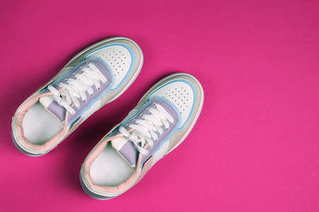 New white sneakers on a bright pink background. Trendy colorful photo in minimal style. Top view, flat lay.の写真素材