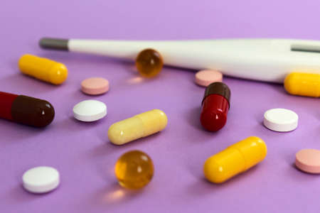 tablets and a thermometer on a purple background