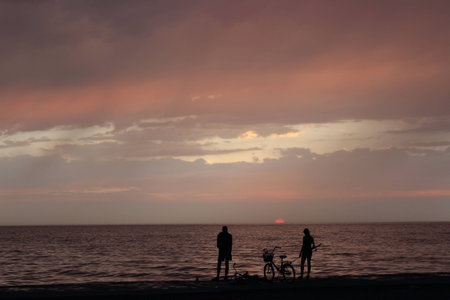 Girl and boy fishing on the sea at sunsetの写真素材