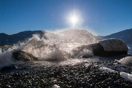 Big waves crash on the stone shore. Teletskoe lake, Altai