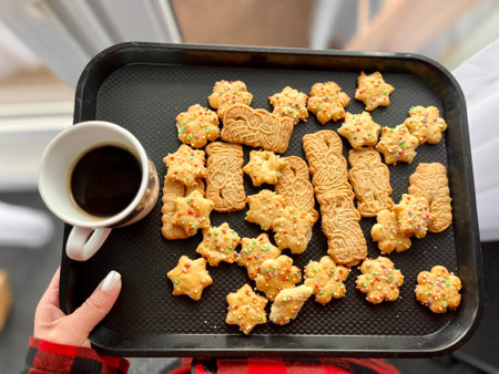 Top view of Christmas gingerbread cookies from raw dough on baking tray, ginger, cinnamon, deer shaping biscuit, freshly backed cookies on red plaid napkin over green. Winter holidays flat lay.の写真素材