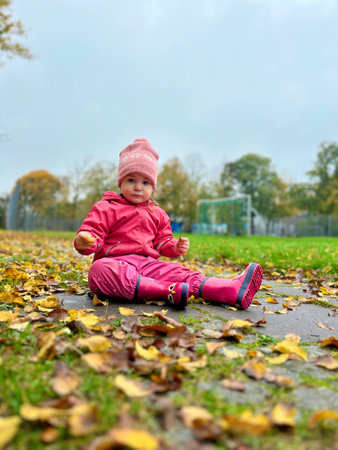 happy child girl throws autumn leaves and laughs outdoors.の写真素材