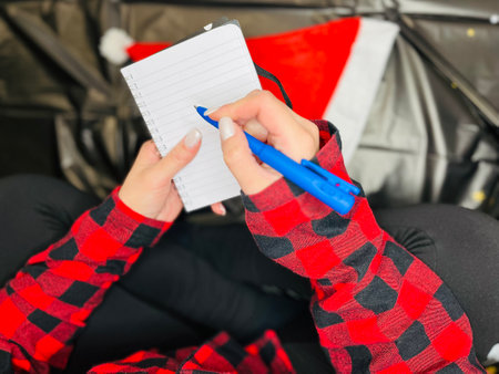 Woman in a knitted sweater sitting on a cozy plaid blanket with Christmas toys and gift box.の写真素材