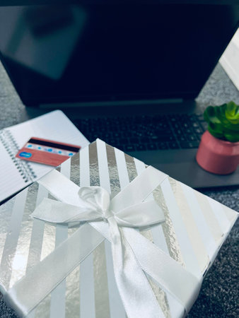 Tech gifts for Christmas for the tech-obsessed person. Gadgets and devices Xmas gift ideas. Laptop with Christmas gift boxes on the table.の写真素材