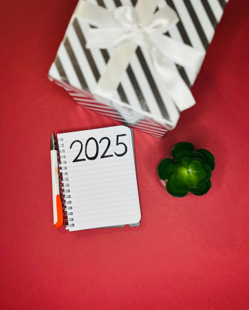 a notebook with a flower and gifts on a red background and the inscription 2025.の写真素材