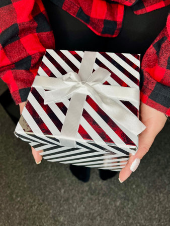 Happy smiling model girl in plaid red dress holding the present box and posing.の写真素材