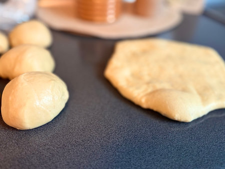 The girl rolls out the dough with a wooden rolling pin for making cupcakes or cookies. Flat composition with kitchen utensils and ingredients, copy space. Concept of baking for the holiday.の写真素材