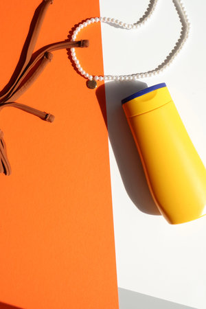 Summer vacation essentials flat lay with striped shorts, sunscreen bottle and pearl bracelet on...