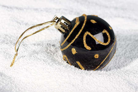 Black Christmas bauble with gold spangles on white snow.の写真素材