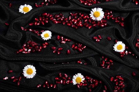 Corns of pomegranate and flowers on black silk fabric .の写真素材