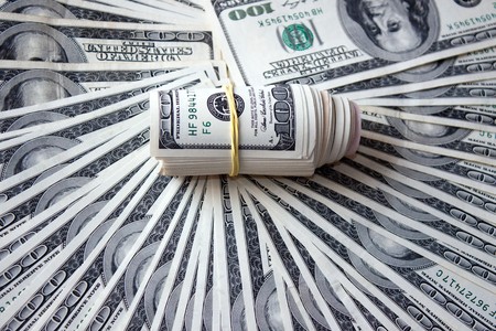 Dollar roll tightened with band on a background of dollarsの写真素材