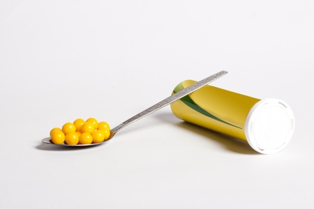 Bottle and full spoon of pills on a white backgroundの写真素材