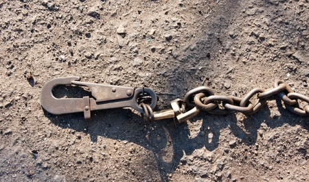 metallic hook and chain lie on earthの写真素材