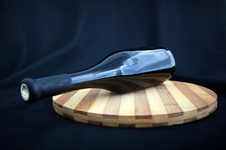 bottle of wine is on the board on a black backgroundの写真素材