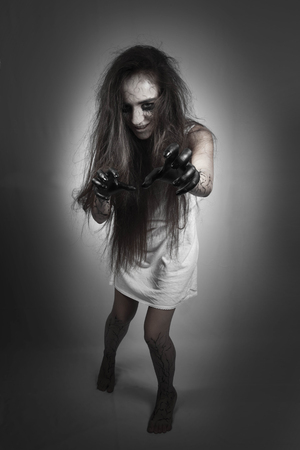 Halloween. obsessed girl with zombies goes and stretches black hands on a black background. concept of halloween and day of the dead.の写真素材