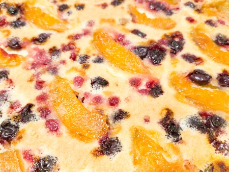Fresh baking cake with fresh cranberries, raspberry, apples and apricots on topの写真素材