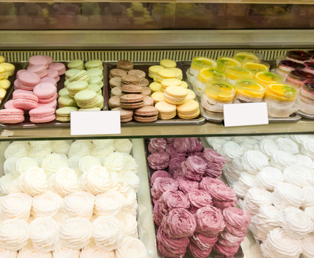 Assortment of Colorful macarons and meringue for sale in shop, price tag. sweets and cakes in candy shop, cafe showcase. Traditional french almond cakes pastry. Variety of flavours.の写真素材