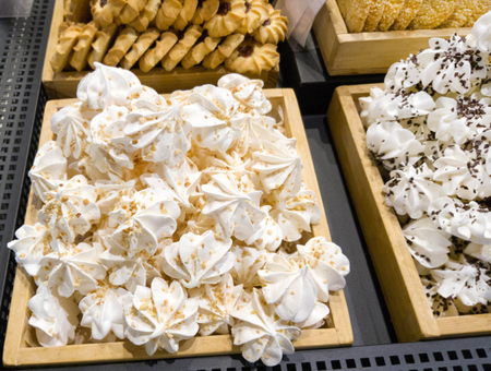 Delicious sweet meringues with nuts and chocolate and biscuits in shop windowの写真素材