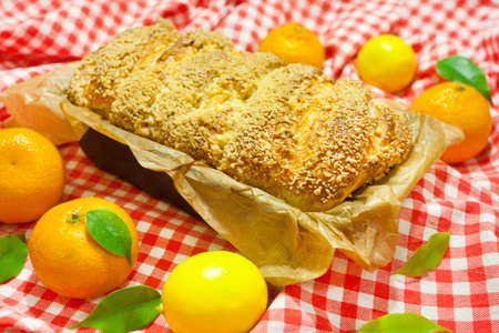 Homemade baking. A hot, aromatic pie with a crispy brown crust. Citrus pie (oranges, tangerines, lemon) in a baking dish. Christmas cake. Red and white checkered fabric background. Rich pastries.の写真素材