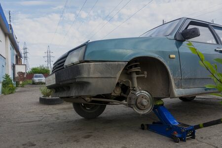 An old car is lifted up without a wheel. Wheel repair, tire fitting.の写真素材