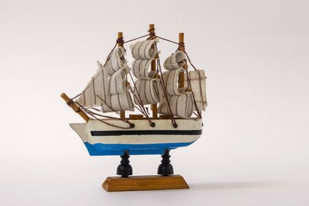 Small toy ship with sails on a white background. Wooden model of a boat. The concept of summer, vacation, sea. The symbol of the ocean.の写真素材